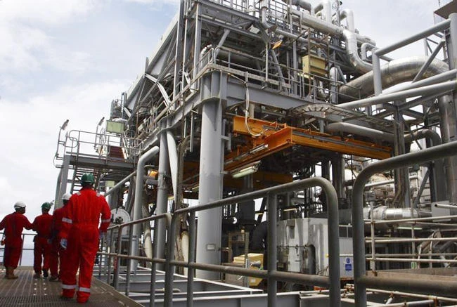Above, oil workers walk through pipe installations on a tanker at Bonga offshore oilfield outside Lagos. (Reuters)