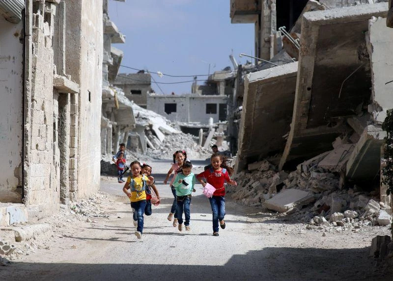 Children run along a damaged street as they celebrate the first day of Eid al-Adha at a rebel-held area in Deraa, Syria, on September 1, 2017. (File photo by Reuters)