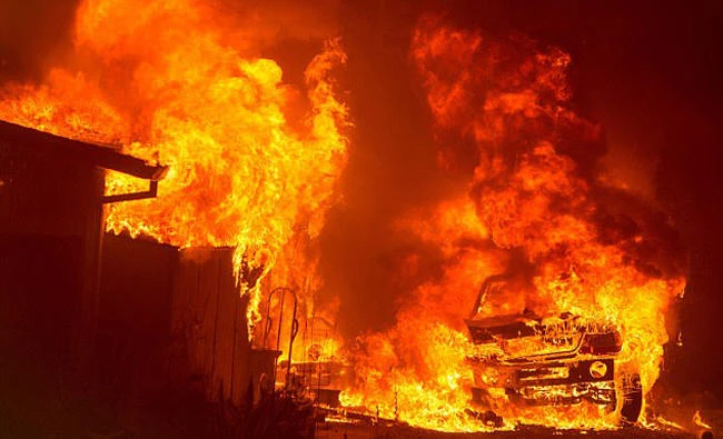 A car and house are engulfed in flames as the 'Wall Fire' burns through a residential area in Oroville on Saturday. (AFP)