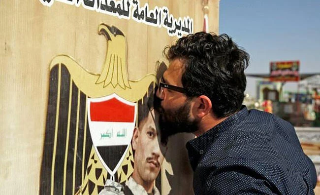 An Iraqi man kisses the grave at Iraq's Wadi Al-Salam cemetery in Najaf of a fighter killed fighting Daesh. (AFP)