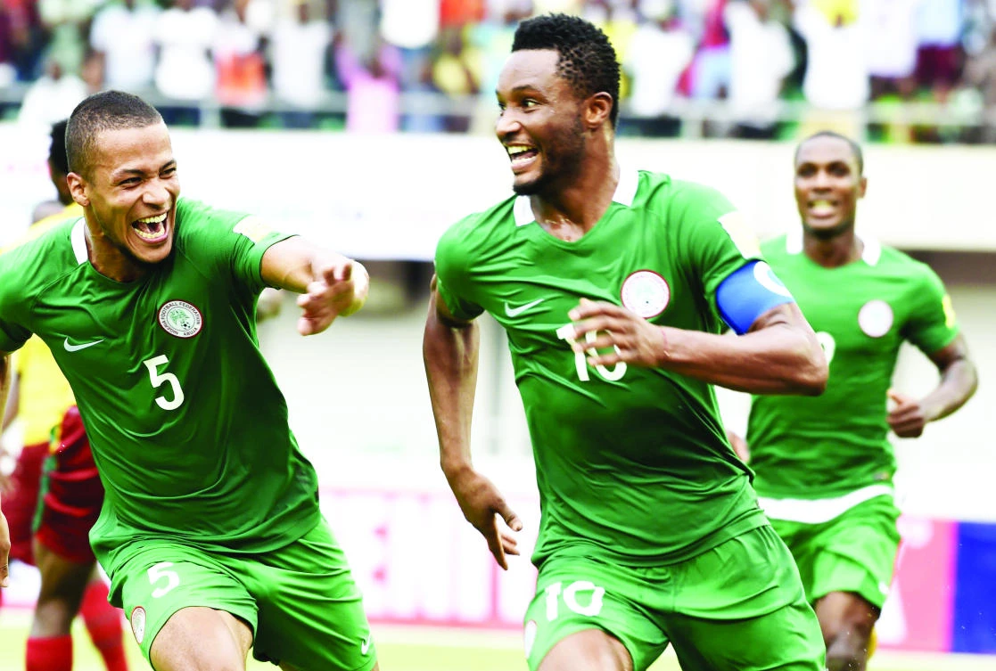 Nigeria's Mikel John Obi, center, celebrates with teammates William Ekong, left, and Odion Ighalo after scoring a goal during the 2018 FIFA World Cup qualifying football match between Nigeria and Cameroon at Godswill Akpabio International Stadium in Uyo, southern Nigeria, on Friday. (AFP)