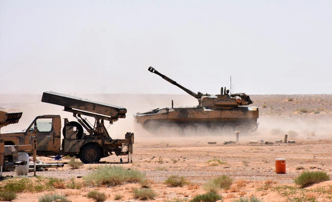 Syrian Army artillery vehicles and rocket launchers stationed near the village of Huraybishah, within the administrative borders of Syria's eastern Deir Ez-Zor province on Sunday. (AFP)
