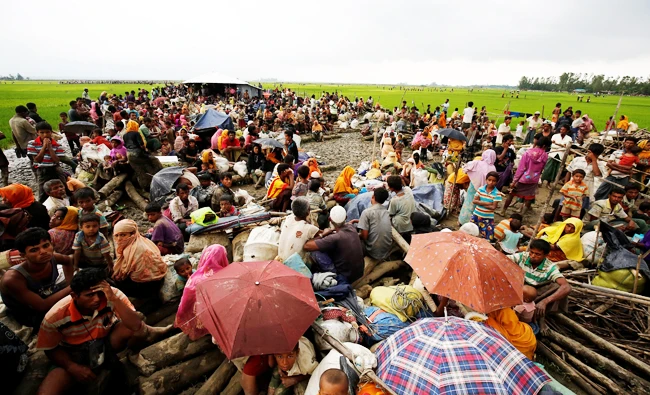 Rohingya refugees sit as they are temporarily held by the Border Guard Bangladesh (BGB) in an open area after crossing the border, in Teknaf, Bangladesh, on Sunday. (REUTERS)