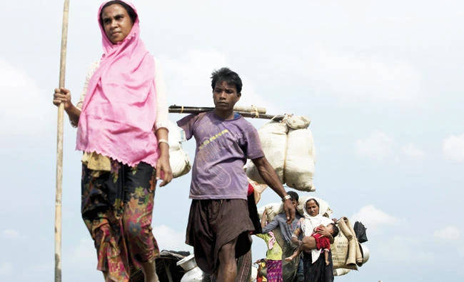 Displaced Rohingya refugees from Rakhine state in Myanmar walk near Ukhia, at the border between Bangladesh and Myanmar, as they flee unrest on Monday. (AFP)