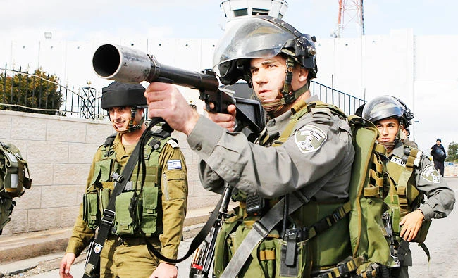 An Israeli border policeman aims his weapon at protesters during a demonstration against the Israeli settlements and demanding for free movement for the Palestinians near a checkpoint in the West Bank city of Bethlehem, in this December 23, 2014 file photo. (REUTERS)