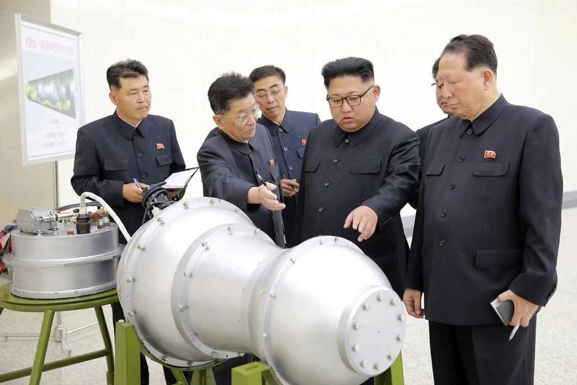 North Korean leader Kim Jong-Un (C) looking at a metal casing with two bulges at an undisclosed location. (AFP/KCNA VIA KNS)