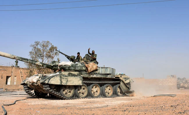 Members of the Syrian government forces raise the victory gesture as they ride on an advancing tank in the village of Kobajjep, on the southwestern outskirts of Deir Al-Zor province, on September 6, 2017, during the ongoing battle against Daeshjihadists. (AFP / George Oourfalian)