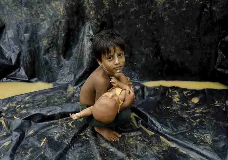 A Rohingya refugee from Myanmar's Rakhine state holds a baby after arriving at a refugee camp near the Bangladeshi town of Teknaf. (AFP)