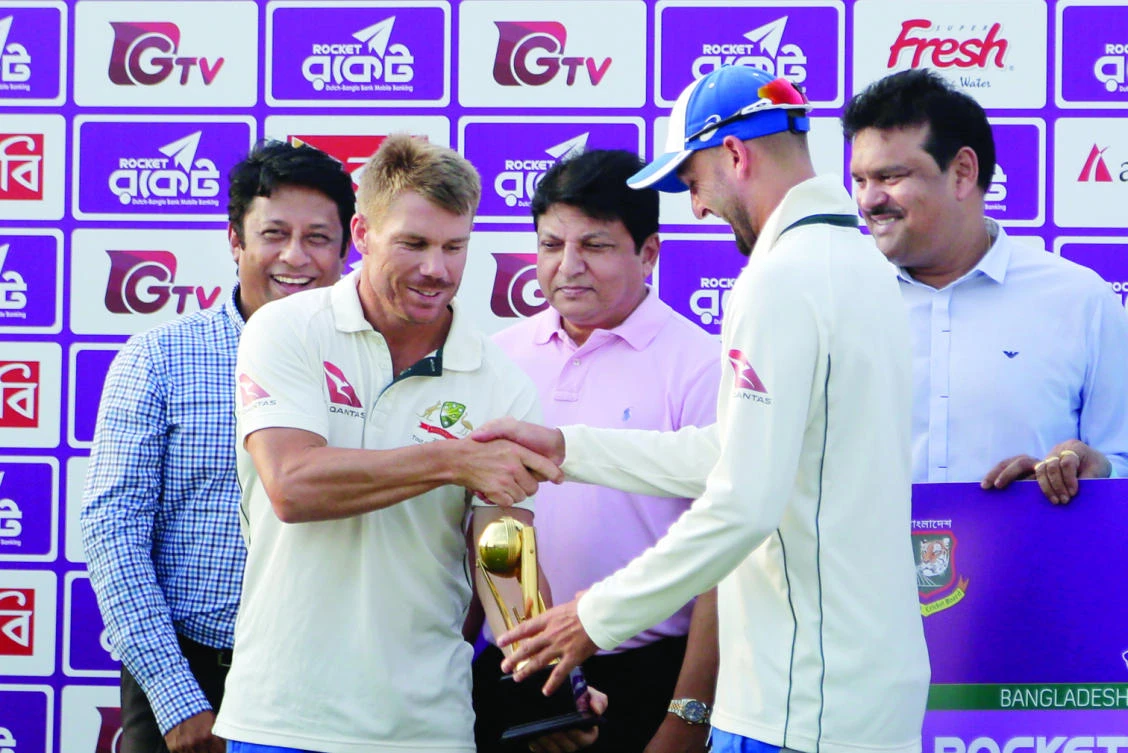 Australia's David Warner, front left, and Nathan Lyon, right, hold the men of the series trophy jointly during a presentation ceremony after the second Test cricket match against Bangladesh in Chittagong, Bangladesh, Thursday. (AP)