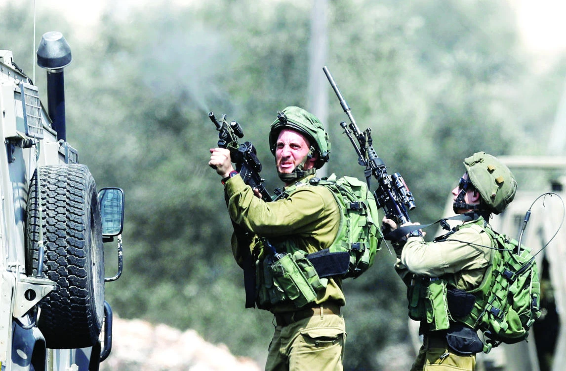 An Israeli soldier fires a weapon during clashes with Palestinians following a protest against the nearby Jewish settlement of Qadomem, in the West Bank village of Kofr Qadom near Nablus. (Reuters)