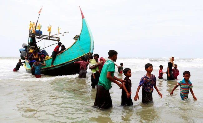 Rohingya refugees walk to the shore after crossing the Bangladesh-Myanmar border by boat through the Bay of Bengal in Teknaf, Bangladesh on Thursday. (REUTERS)
