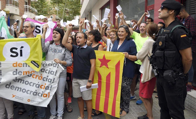 People hold up ballots for the Catalan referendum on independence as they protest against a police search in the headquarters of the weekly newspaper "El Vallenc" in Valls, on Saturday. (AFP)