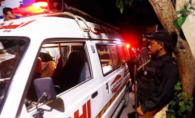 A policeman stands as one of the ambulances carrying bodies, which according to Edhi Foundation's rescue workers were the 13 picnickers who drowned at Hawks Bay beach and were later recovered, arrive outside the hospital morgue in Karachi, Pakistan on Saturday. (REUTERS)