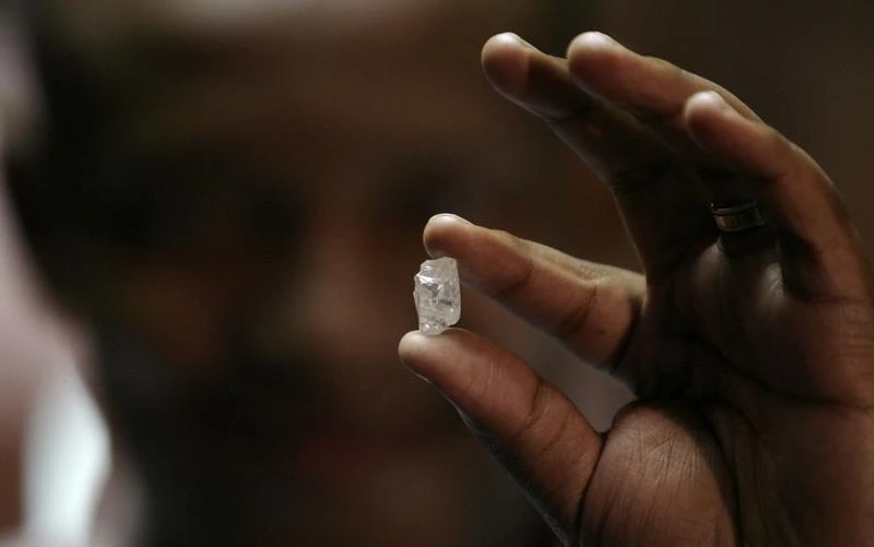 Above, a visitor holds a 17-carat diamond at a Petra Diamonds mine. (Reuters)