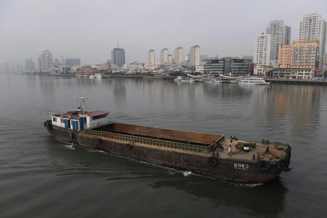 A North Korean ship passes in front of the waterfront of the Chinese border city of Dandong (at rear), in China's northeast Liaoning province, opposite the North Korean town of Sinuiju on September 4, 2017. (AFP)