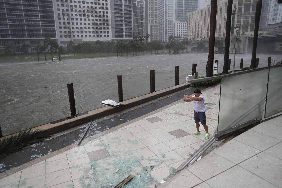 A person battles high winds and rain to take pictures of the flooding along the Miami River as Hurricane Irma passes through on September 10, 2017 in Miami, Florida. Hurricane Irma made landfall in the Florida Keys as a Category 4 storm on Sunday, lashing the state with 130 mph winds as it moves up the coast. (AFP)