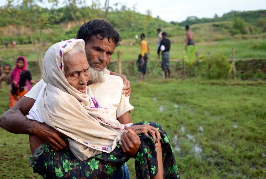 This file photo shows a Rohingya man carrying his mother in Ukhiya after crossing the Bangladesh-Myanmar border on August 30, 2017. (File photo by AFP)