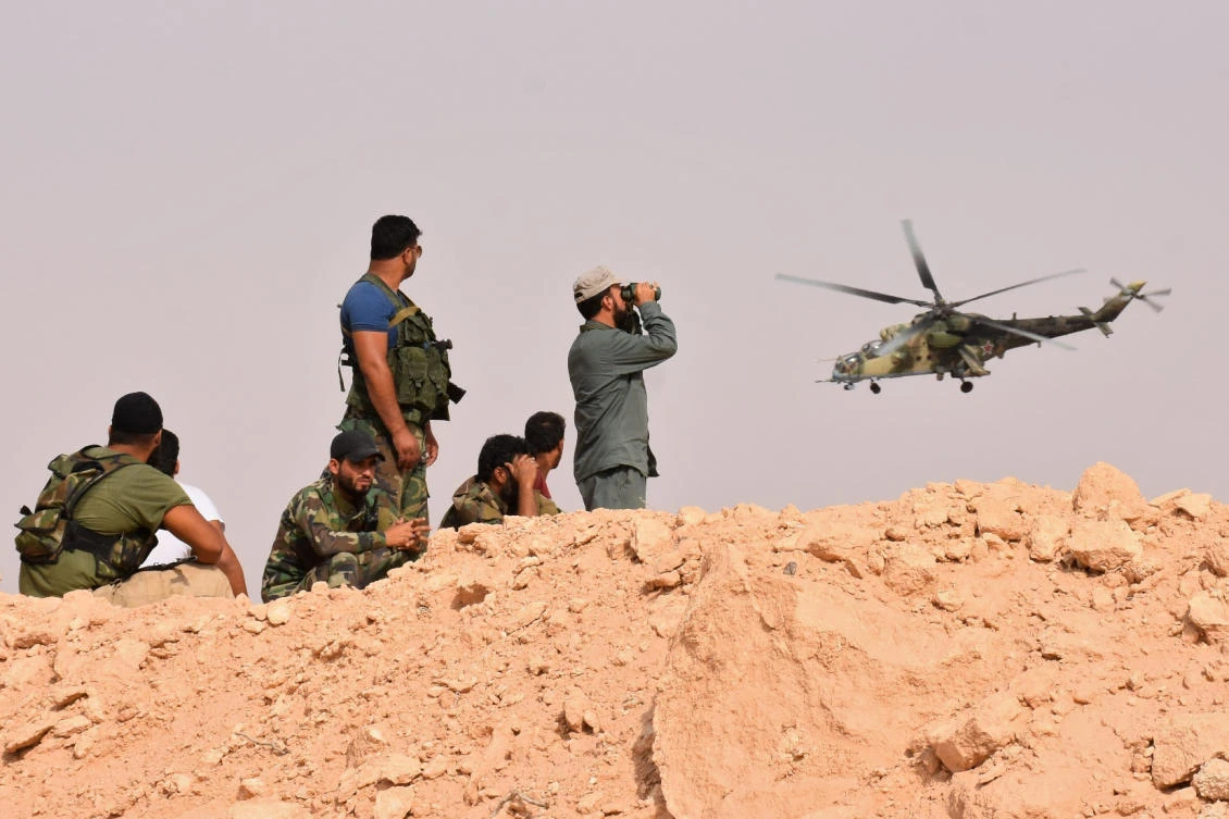 A Russian army helicopter flies over Syrian government forces holding a position in Kobajjep area, on the southwestern outskirts of Deir Ezzor. (AFP)