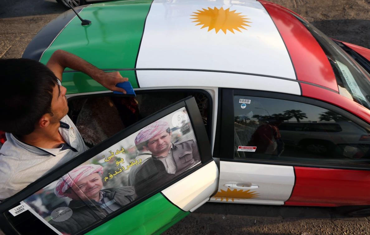An Iraqi Kurdish man decorates a car with the Kurdish flag. (AFP)
