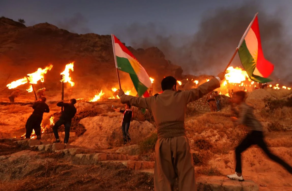 Iraqi Kurds wave Kurdish flags and hold burning torches as they walk up a mountain during a gathering to show support for the upcoming independence referendum. (AFP)