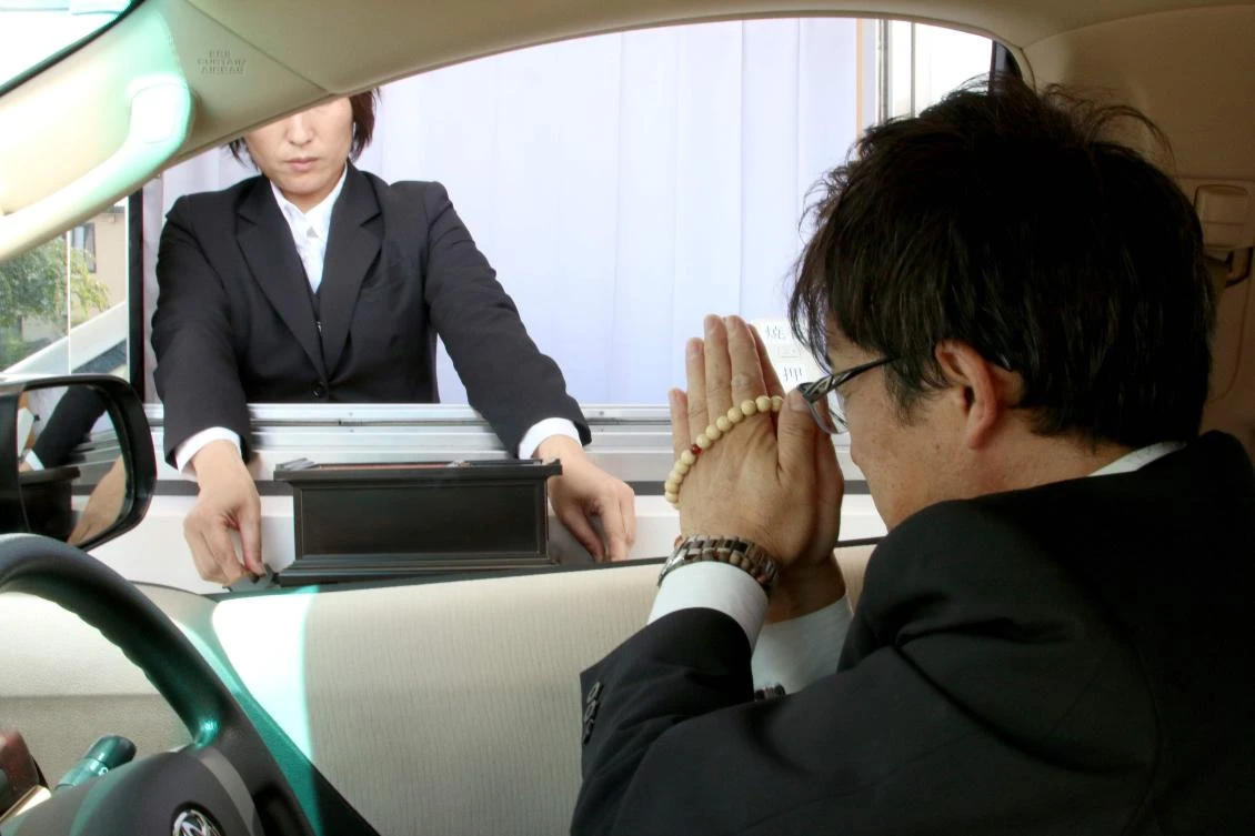A driver offering funeral prayers in his car in Ueda, Nagano prefecture, in this undated handout photo taken recently and released by Kankon Sosai Aichi Group, on September 13, 2017. (Kankon Sosai Aichi Group via AFP)
