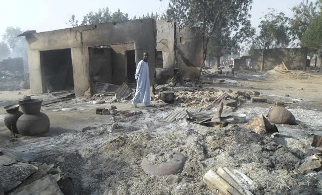 In this Jan. 31, 2016 file photo, a man walks past burnt out houses following an attack by Boko Haram terrorists in Dalori village near Maiduguri. (AP Photo/Jossy Ola, File)