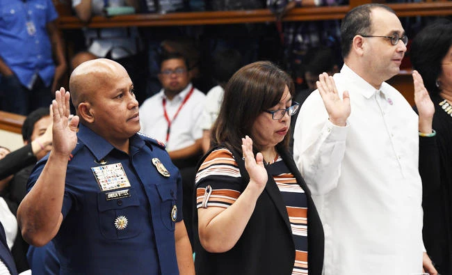 This file photo taken on August 22, 2016 shows Philippine National Police (PNP) Director General Roland dela Rosa (L) and Commission on Human Rights Commissioner Chito Gascon (R) taking their oaths at the start of a senate inquiry into a spate of extrajudicial killings in Manila. (AFP)