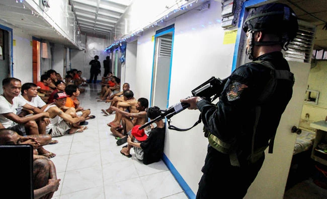 National Bureau of Investigation (NBI) operatives round up inmates inside New Bilibid Prison in Muntinlupa, south of Manila, in this December 16, 2014 file photo. (AFP)