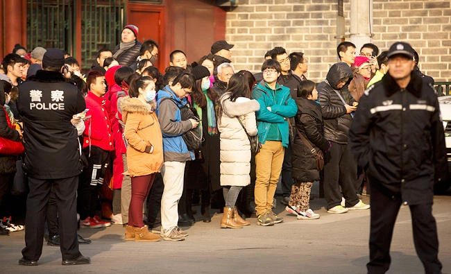 In this Jan. 1, 2016 file photo, policemen watch as depositors from Ezubo gather outside the State Bureau for Letters and Calls Reception Division office in Beijing. (AP)