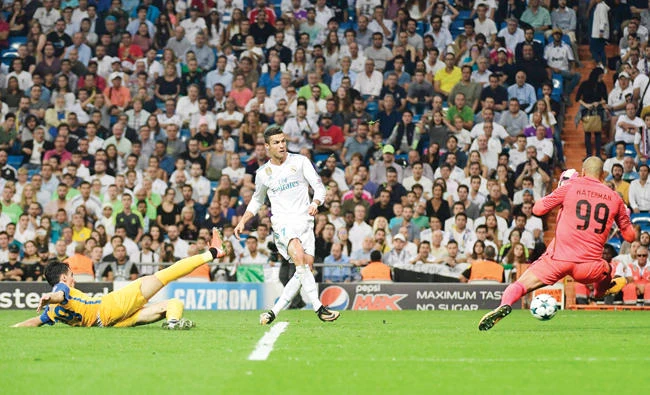 Real Madrid’s forward from Portugal Cristiano Ronaldo, center, kicks the ball past APOEL Nicosia’s goalkeeper from the Netherlands Boy Waterman during the UEFA Champions League football match Real Madrid CF vs. APOEL FC at the Santiago Bernabeu stadium in Madrid on Wednesday. (AFP)