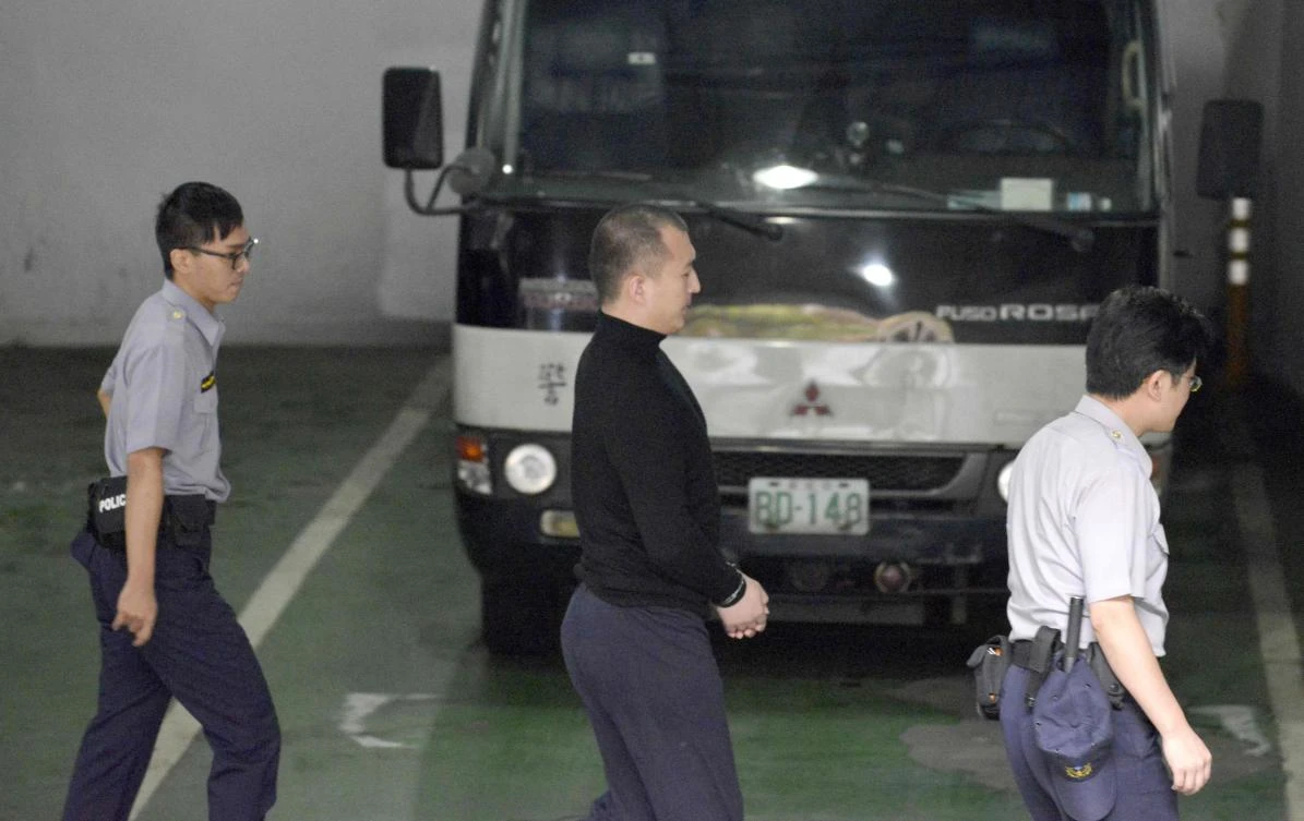 Zhou Hongxu, center, a Chinese student from Taiwan’s National Chengchi University last year, is escorted by policemen at the Taipei District Court on Friday, September 15. (AFP)