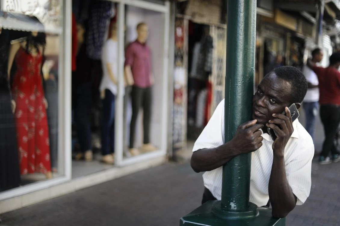 An African migrant uses a mobile phone in Neve Shaanan street in southern Tel Aviv on September 4, 2017. / AFP / MENAHEM KAHANA