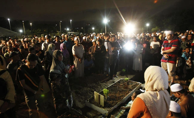 People pray during a mass burial of mostly young boys who died in a fire at a private boarding school, at a cemetery on the outskirts of Kuala Lumpur, Malaysia on Friday, Sept. 15, 2017. (AP Photo/Daniel Chan)