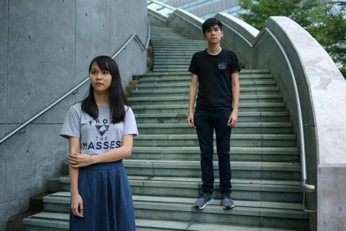 In this picture taken on August 29, 2017, Hong Kong democracy activists Agnes Chow (L) and Lester Shum pose for photos outside the Hong Kong government headquarters. The jailing of Hong Kong's best-known democracy activists has pushed a new wave of young leaders to take the helm as they seek to keep the movement's message alive. - TO GO WITH Hong Kong-China-politics-democracy, FOCUS by Aaron TAM / AFP / Aaron TAM / TO GO WITH Hong Kong-China-politics-democracy, FOCUS by Aaron TAM