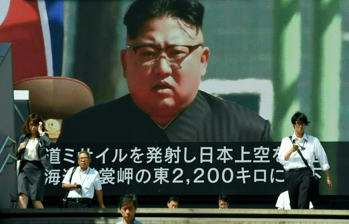 Pedestrians walk in front of a large video screen in Tokyo broadcasting a news report showing North Korean leader Kim Jong-Un, following a North Korean missile test that passed over Japan on September 15, 2017. (File photo by AFP)