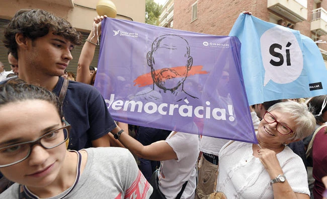A woman holds a banner demanding democracy during a demonstration against a police search in the headquarters of the weekly newspaper "El Vallenc" in Valls, on September 9, 2017. The Spanish Civil Guard searched today "El Vallenc" newspaper's headquarters in Valls, which would be suspected of having printed ballots for the banned referendum on independence in Catalonia, convened for October 1. (AFP)