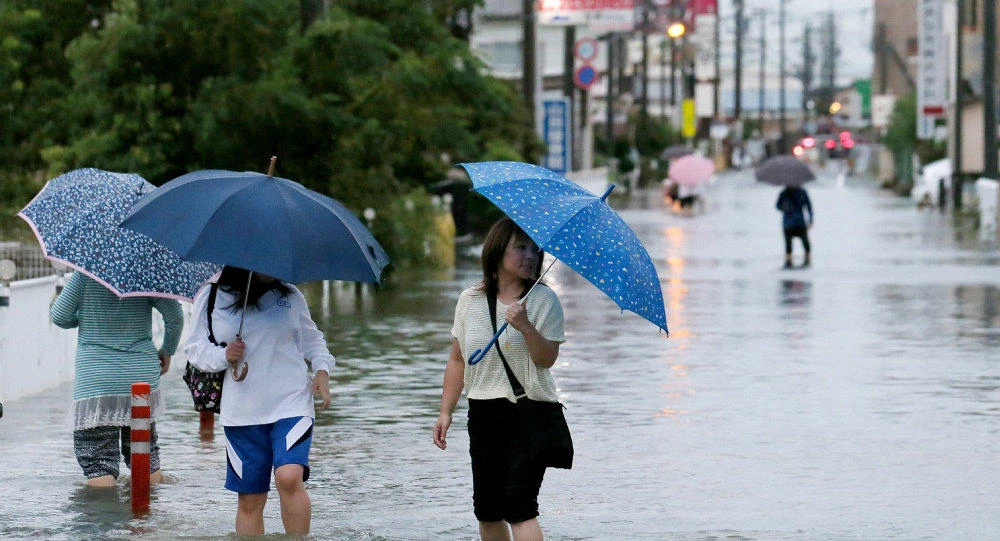 Pedestrians wade through flood waters on a road following torrential rains brought on by Typhoon Etau. (AFP)
