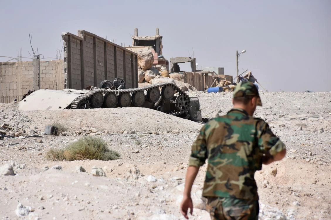 A Syrian pro-government force walks past an upside-down tank in the Jamiyet Al-Ruwad neighborhood on the northern outskirts of Deir Ezzor. (AFP)
