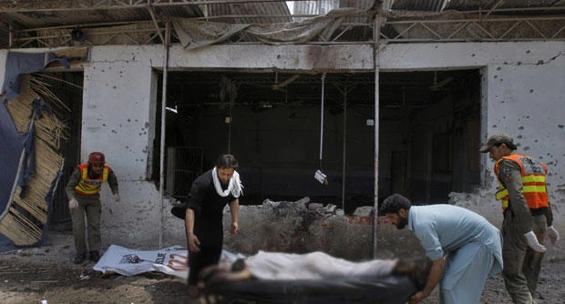 Pakistani volunteers and rescue workers remove a lifeless body from the site after a bomb explosion in Peshawar, Pakistan, Sunday, May 11, 2014. A police official in Pakistan says a bomb blast targeting refugees registering with the government has killed several people in northwestern city of Peshawar. Faisal Mukhtar says the bombing Sunday on a soccer field also wounded many people. He says it happened as officials registered refugees from the nearby Khyber tribal region. (AP)
