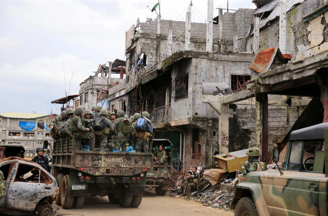 A military truck full of government soldiers move past damaged houses and buildings as troops continue their assault on clearing operations against the pro-IS militant group which seized Mapandi district in Marawi city, southern Philippines, September 13, 2017. (REUTERS)