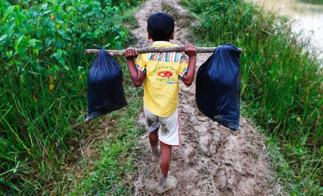 A Rohingya refugee boy carries his belongings as he walks to a makeshift camp in Cox's Bazar, Bangladesh September 18, 2017. REUTERS/Danish Siddiqui