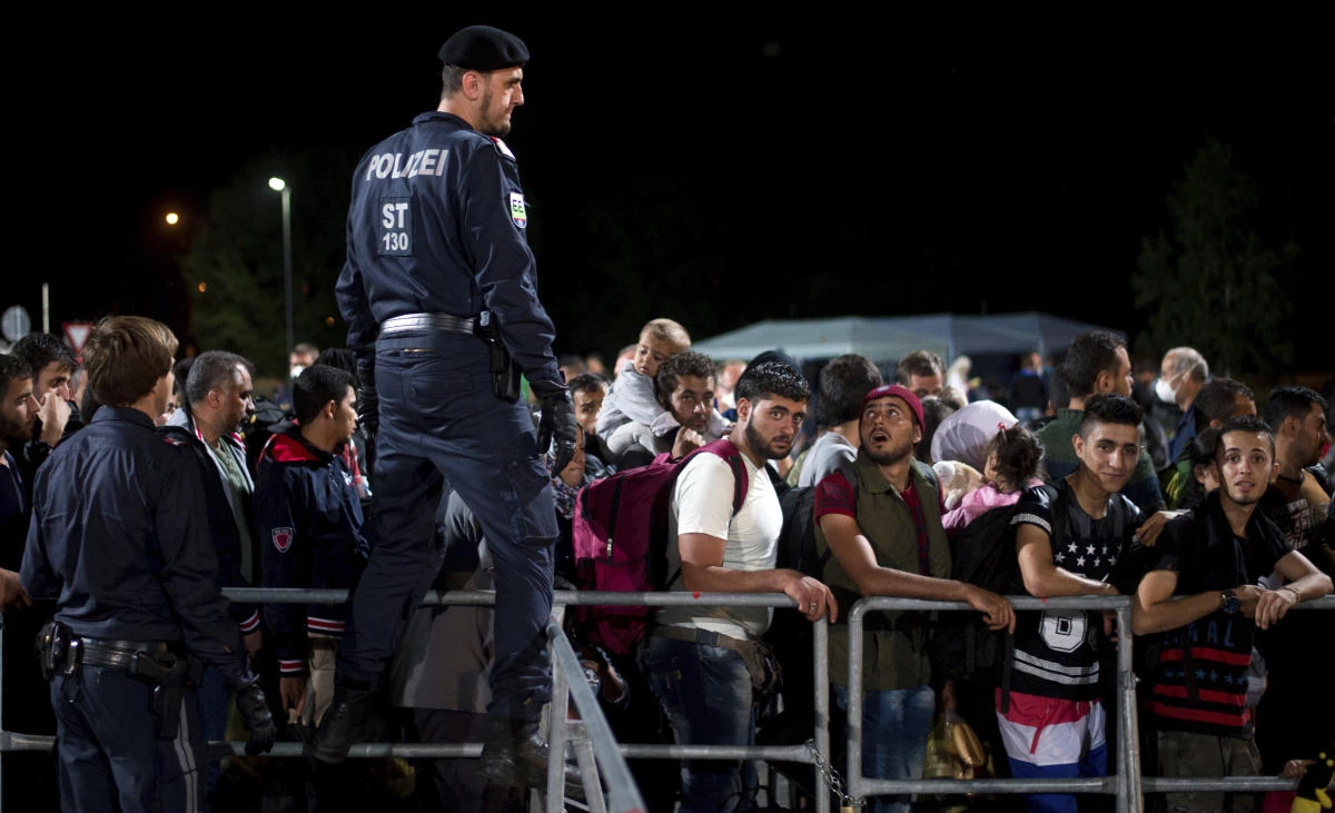 In this file photo dated Sept. 15, 2015, refugees queue as they arrive at the border between Austria and Hungary, at Heiligenkreuz, Austria. An Austrian court on Monday sentenced to jail a man who posted a call for the reopening of a Hitler-era concentration camp and the gassing of migrants there. (AP Photo/Christian Bruna, FILE)