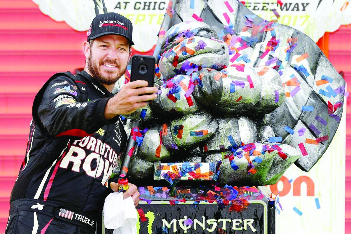 Martin Truex Jr., driver of the #78 Furniture Row/Denver Mattress Toyota, takes a selfie with the trophy in Victory Lane after winning the Monster Energy NASCAR Cup Series Tales of the Turtles 400 at Chicagoland Speedway on Sunday. (AFP)