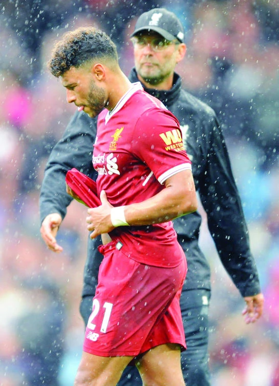 Liverpool’s coach Juergen Klopp, rear, and player Alex Oxlade-Chamberlain, front, walk on the pitch during heavy rainfall after the English Premier League soccer match between Manchester City and Liverpool at the Etihad Stadium in Manchester, England, on Saturday. (AP)