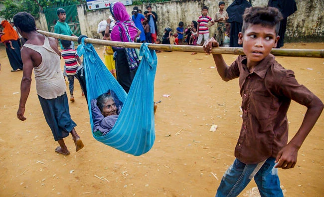 A Rohingya Muslim woman Lalmoti is carried to hospital by her son and grandson in Kutupalong refugee camp, Bangladesh, on Monday. (AP)
