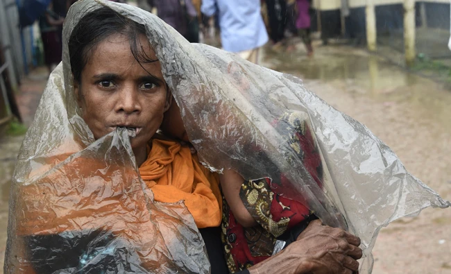 A Rohingya Muslim refugee shelters from the rain at Leda refugee camp near the Bangladehsi district of Teknaf on Tuesday. (AFP)