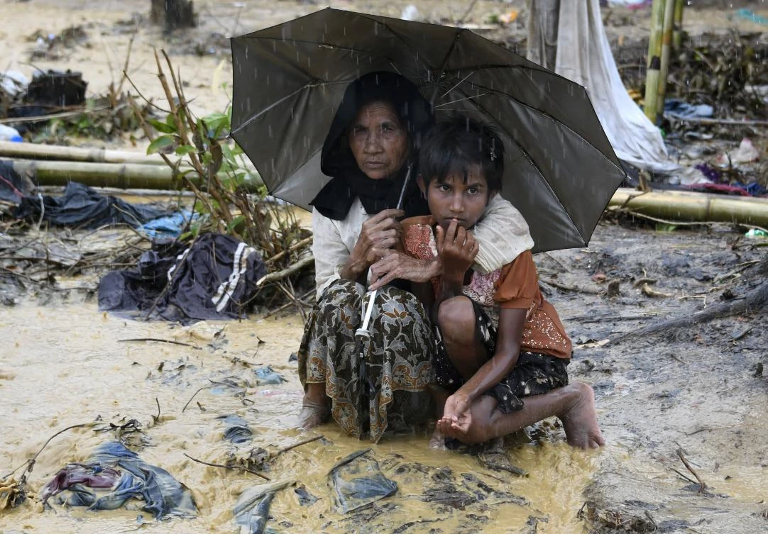 Rohingya refugees shelter under an umbrella during rain in Bangladesh's Balukhali refugee camp. (AFP)