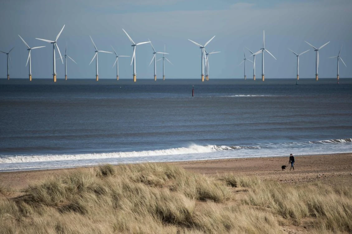 A woman walking her dog along the beach in front of an off-shore wind farm near Hartlepool, north east England. (AFP)