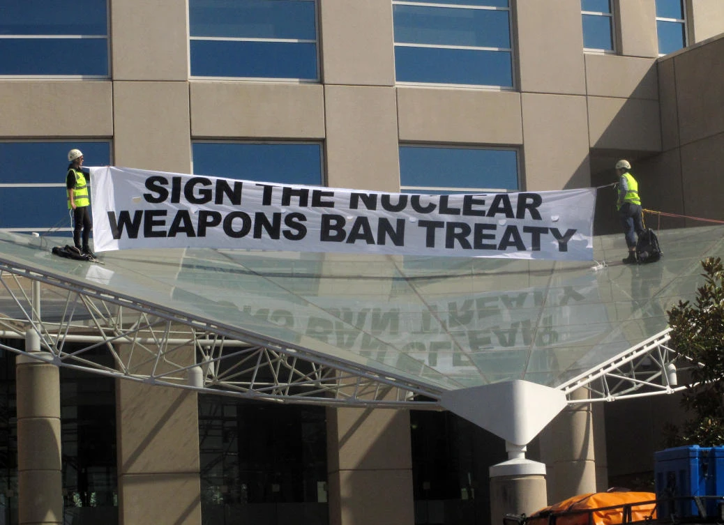 Two anti-nuclear weapons campaigners Gem Romuld, left, and Papatya Danis unfurl a banner at the Department of Foreign Affairs and Trade building in Canberra Wednesday, Sept. 20, 2017, to protest the government's failure to endorse a United Nations' nuclear disarmament treaty. (AP Photo/Rod McGuirk)
