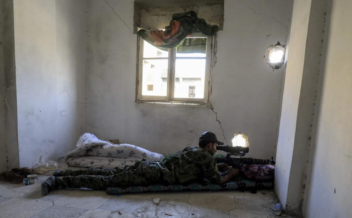 A member of the Syrian Democratic Forces (SDF), a US backed Kurdish-Arab alliance, looks through the scope of a sniper rifle as he lies in a flat in the western Al-Daraiya neighborhood of the embattled northern Syrian city of Raqqa. (AFP)
